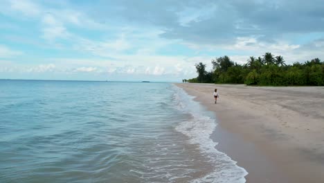 Girl-With-A-Backpack-Is-Walking-In-The-Shoreline-Of-Langkawi-Beach-Tropical-Island,-Malaysia