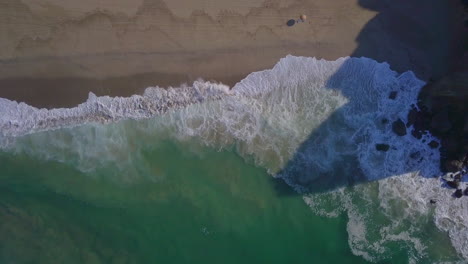 Absteigende-Luftaufnahme-In-Zeitlupe-Eines-Atemberaubenden-Strandes-Mit-Brechenden-Wellen