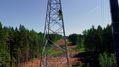 Aerial-view-of-professional-workers-working-on-the-installation-of-a-high-voltage-tower-in-a-forest-firebreak