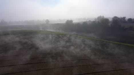 Flying-Over-Rural-Field-With-Thick-Fog-In-Daytime
