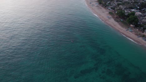 fishing-close-by-rural-beach-village-above-corals,-aerial-rotating-view