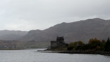 Eilean-Donan-Castle,-Highlands,-Scotland,-with-dark-moody-skies-and-clouds-and-mountains
