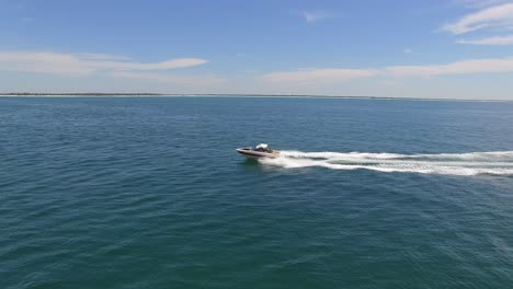 Powerboat-Moviéndose-Rápido-A-Través-Del-Océano-En-La-Soleada-Tarde-Seguimiento-Lateral-Aéreo