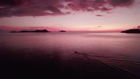 Boot,-Das-Während-Des-Roten-Postsonnenuntergangs-Mit-Inseln-Im-Hintergrund-Auf-See-Fährt