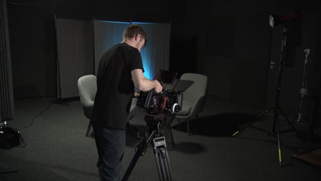 a-person-puts-a-red-cinema-camera-on-a-tripod-in-a-studio