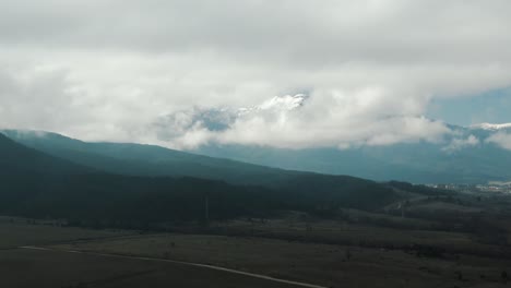 Toma-De-Un-Dron-De-Un-Campo-Y-Una-Montaña-Con-Cielo-Nublado
