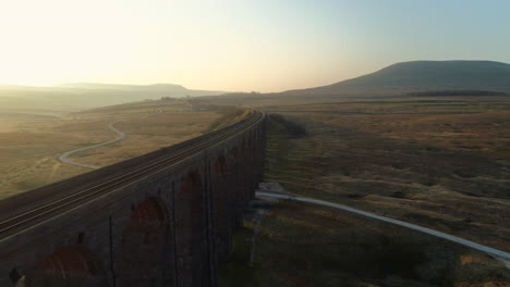 Aerial-Drone-Shot-Close-Along-Ribblehead-Viaduct-Train-Bridge-at-Stunning-Sunrise-in-Summer-in-Yorkshire-Dales-England-UK-with-3-Peaks-Ingleborough-in-Background