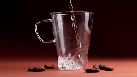 Pouring-Hot-Water-In-Transparent-Glass-With-Cashew-Nuts-All-Around