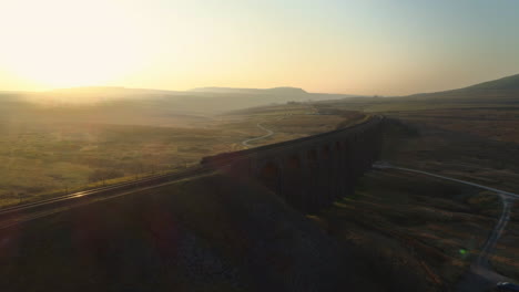 Low-Close-Aerial-Drone-Shot-Rotating-Around-Ribblehead-Viaduct-Train-Bridge-at-Stunning-Sunrise-in-Summer-in-Yorkshire-Dales-England-UK-with-3-Peaks-Ingleborough-Mountain-in-Background