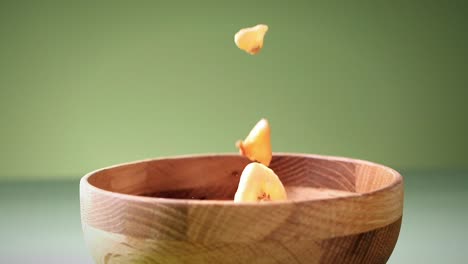 Slow-Motion-Shot-Of-Dried-Fruits-Falling-In-wooden-Bowl-In-Green-Background