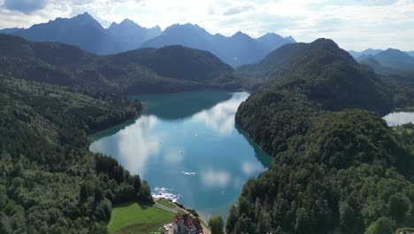 Lago-Alpsee-En-Alemania-Cerca-De-Fussen-Drone-Vista-Aérea-Día-Soleado-Nubes-Reflejándose-En-El-Lago