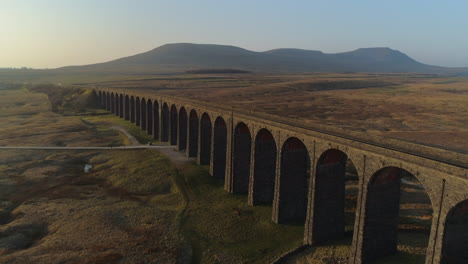 Low-Aerial-Drone-Shot-Closeup-to-Ribblehead-Viaduct-Train-Bridge-at-Stunning-Sunrise-in-Summer-in-Yorkshire-Dales-England-UK-with-3-Peaks-Ingleborough-Mountain-in-Background