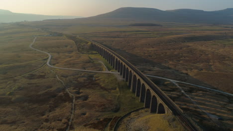 High-Aerial-Drone-Shot-Rotating-Around-Ribblehead-Viaduct-Train-Bridge-at-Stunning-Sunrise-in-Summer-in-Yorkshire-Dales-England-UK-with-Ingleborough-in-background