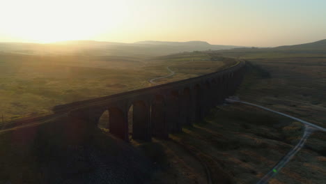 Luftdrohnenaufnahme-Der-Ribblehead-Viadukt-Zugbrücke-Bei-Atemberaubendem-Sonnenaufgang-Im-Sommer-In-Yorkshire-Dales-England-Großbritannien-Mit-Hügeln-Im-Hintergrund