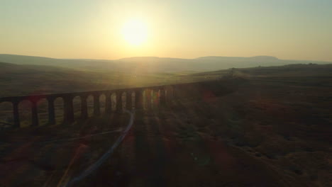 Aerial-Drone-Shot-of-Silhouetted-Ribblehead-Viaduct-Train-Bridge-at-Stunning-Sunrise-in-Summer-in-Yorkshire-Dales-England-UK-with-Hills-in-Background