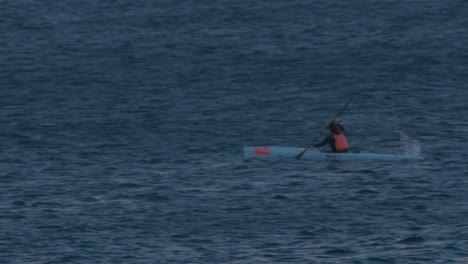 aerial-view-of-professional-canoeist-riding-very-quickly-in-the-sea-entering-the-night,-Cascais,-Portugal