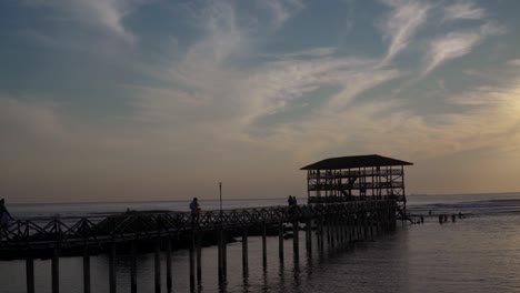 Zeitlupenaufnahme-Von-Touristen,-Die-Einen-Silhouettensonnenuntergang-Am-Strand-Von-Einem-Pier-In-Siargao,-Philippinen,-Genießen