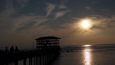 Slow-motion-shot-of-the-pier-at-sunset,-The-silhouettes-of-a-low-tide-in-the-Philippines