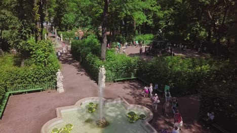Summer-Garden,-an-aerial-drone-footage-in-a-park-with-a-statue,-fountain-and-people