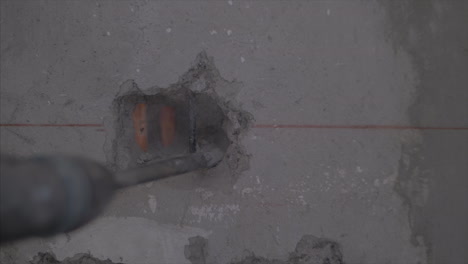 Close-up-of-a-hammer-drill-making-a-hole-on-the-wall-for-the-light-switch-to-be-install,-in-Full-HD-at-60-fps