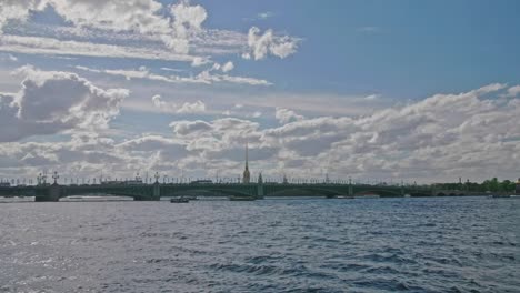 View-on-Saint-Petersburg-Neva-river,-Peter-and-Paul-cathedral,-blue-water,-castle,-boats,-park-in-a-distance,-deep-sky-with-clouds