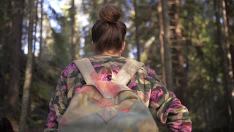 Young-woman-with-a-bag-walks-in-a-forest-with-brown-hair-and-blurry-background-in-slow-motion