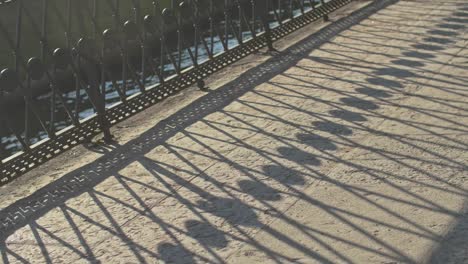 Slow-motion-moody-slide-by-the-river-with-shadows-of-the-fence,-metal-frame,-sunny-summer-garden,-saint-petersburg