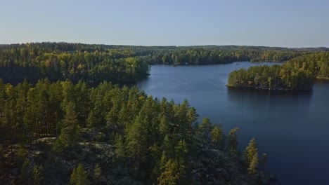 Aerial-shot-epic-shot-of-a-nordic-forest-in-Finland,-national-park-with-islands-and-forest,-stone-shores-and-deep-blue-water