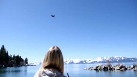 Mujer-Volando-Drone-En-Una-Playa-En-El-Lago-Tahoe,-Nv