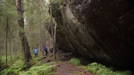 Huge-forest-stone-with-trees-in-Finland,-Pirrunkirkko,-mountain,-rock-tourists-walking-in-National-Park