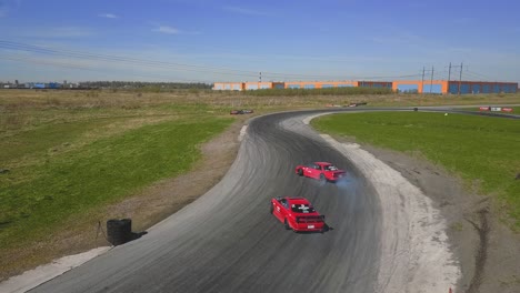 Two-red-racing-drift-cars-doing-a-parallel-drift-on-a-track
