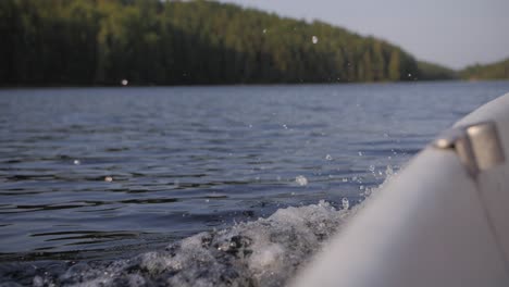 Big-wave-and-ripples-on-a-lake-while-in-a-boat-with-sun-shining-in-the-background-blurry-forest-moody-evening-atmoshere