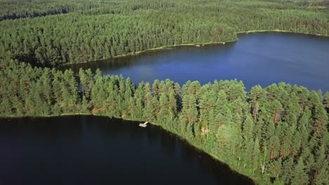 Aerial-footage-of-a-Finnish-lake-in-summer,-blue-sky,-heavy-clouds-and-sun,-small-pierce-in-a-forest,-national-park