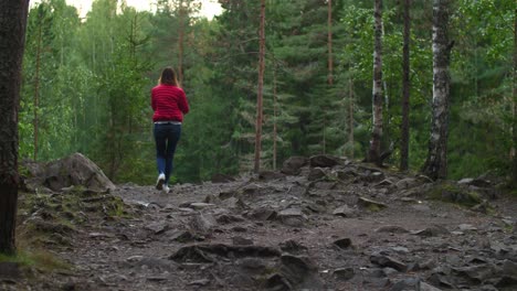 Woman-in-red-jacket-and-blue-jeans-walking-on-Karelian-rocks-with-moss-and-plants-in-4k-50-fps,-slow-motion