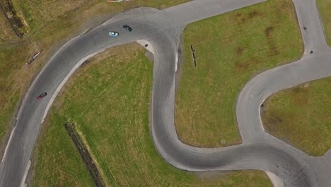 Top-down-aerial-still-view-on-a-race-track-with-drifting-cars,-smoking-tires-and-sunny-weather