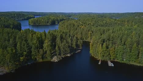 Floating-bridge-on-ropes-over-a-lake-or-a-stream-in-a-forest,-summer,-aerial-epic-wide-shot-with-islands,-lakes-and-forest