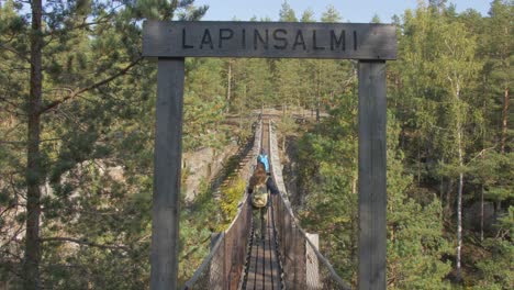 People-walking-over-a-floating-bridge-in-Lapinsalmi,-Finland,-slow-motion