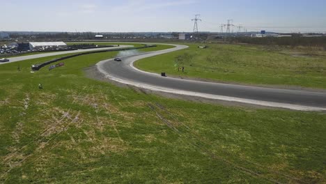 Wide-aerial-shot-of-a-drifting-car-on-a-race-track-with-smoking-tires-and-sunny-weather