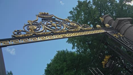Slow-motion-footage-of-a-Royal-entrance-to-Summer-Garden,-Saint-Petersburg-with-golden-elements,-old-ornaments,-blue-sky
