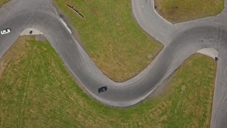 Drifting-race-car-on-a-track-going-into-a-s-turn,-aerial-top-down-shot