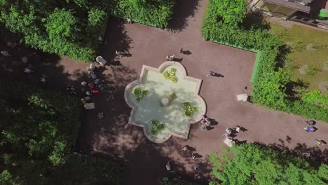 Summer-Garden,-an-aerial-drone-footage-of-a-fountain-on-a-3rd-alley,-fly-in-over-the-top,-straight-down-looking-shot,-people-walking-in-a-park,-ancient-greek-statues,-flowers