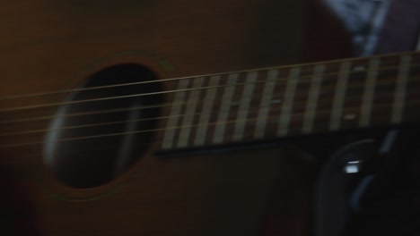 A-close-up-of-a-young-man-is-playing-guitar,-the-camera-pans-right-to-show-his-chord-hand