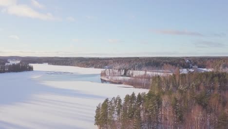 Aerial-over-a-frozen-lake-with-sun-shining-and-green-pine-trees