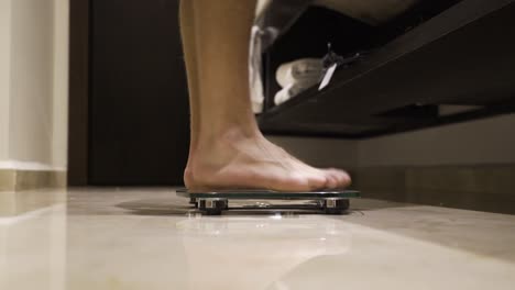 Skinny-boy-steps-onto-weighing-scale,-MEDIUM