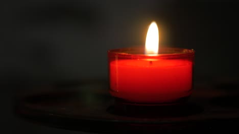 Burning-red-candle-isolated-on-black-background,-resembles-concepts-of-religion,-romance-love-and-festivity