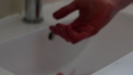 Die-Hände-Eines-Mannes-Triefen-Vor-Blut,-Dann-Beginnt-Er,-Sie-In-Einem-Waschbecken-Zu-Waschen