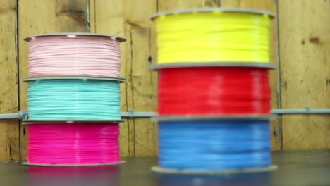 Two-piles-of-3D-Printer-filament-sit-on-a-workshop,-the-camera-racks-focus-between-the-two-of-them