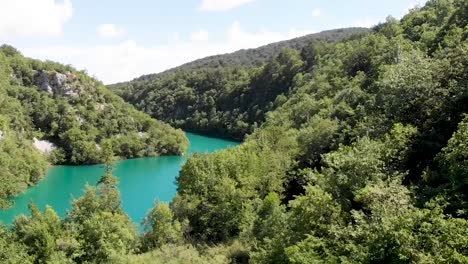 Descending-drone-shot-in-a-green-valley-with-a-stunning-blue-lake