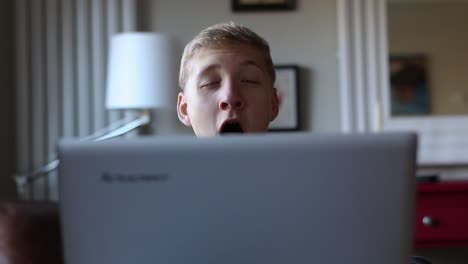 Drowsy-Teenager-Yawns-While-Surfing-on-His-Laptop