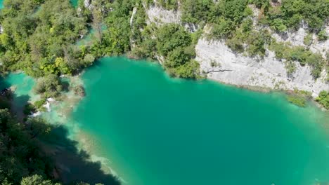 Ascending-drone-shot-of-a-lake-with-rocks-and-lush-green-trees